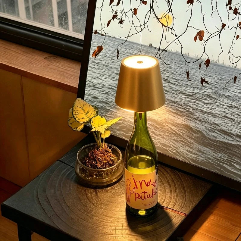 Tête de lampe BottleGlow dorée sur une bouteille verte à côté d'œuvres d'art encadrées