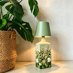Tête de lampe BottleGlow verte sur une bouteille florale à côté d'une plante d'intérieur