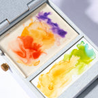 Two ceramic mixing surfaces of the Field Studio travel palette with watercolor washes