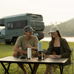 Two people using OutIn Nano 2 espresso machines at a campsite table