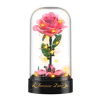 Rosa Rosen-Bauset unter der transparenten Haube mit eingeschalteter warmweißer LED-Lichterkette