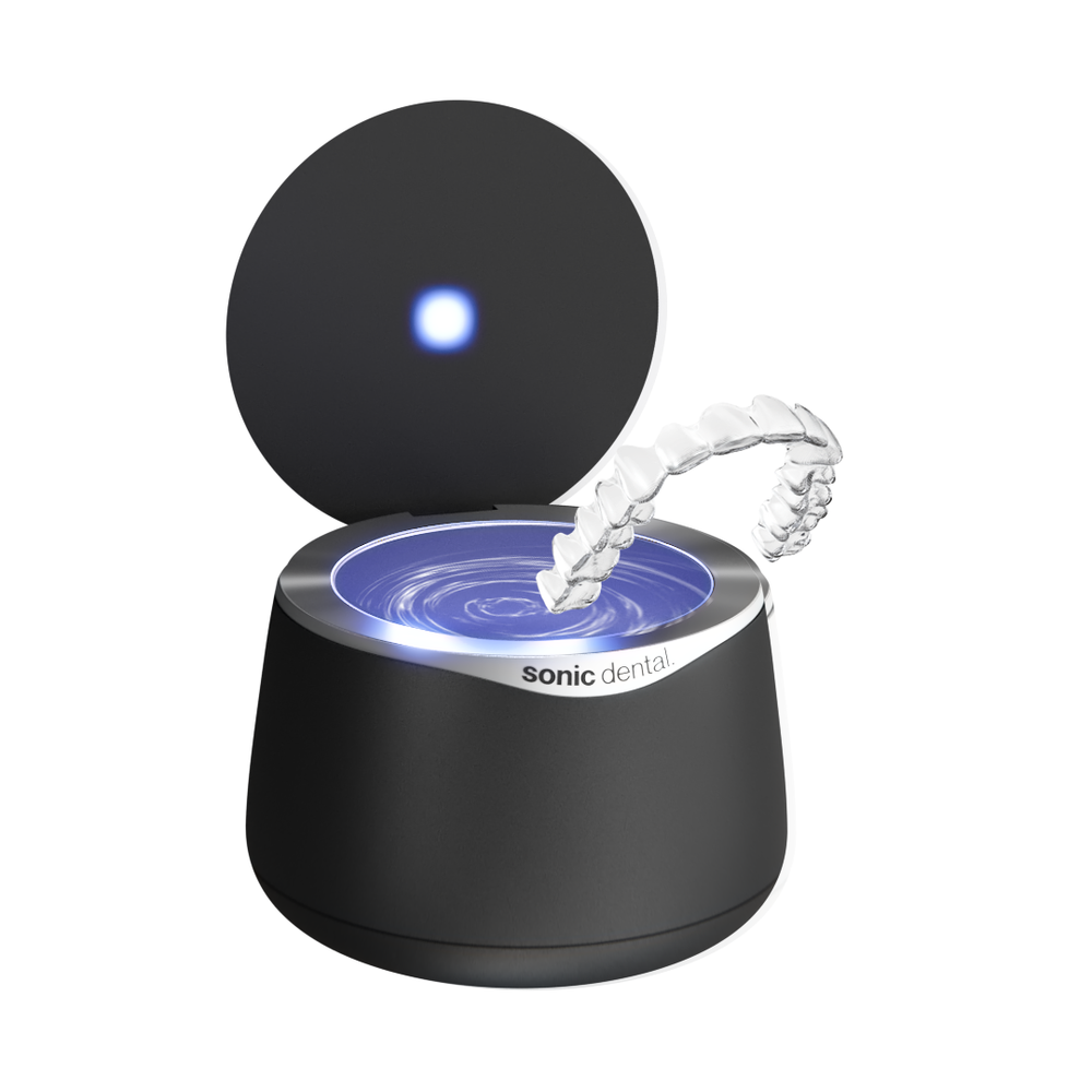 Nettoyeur Sonic Pro noir avec son couvercle ouvert et un appareil dentaire transparent au-dessus du réservoir