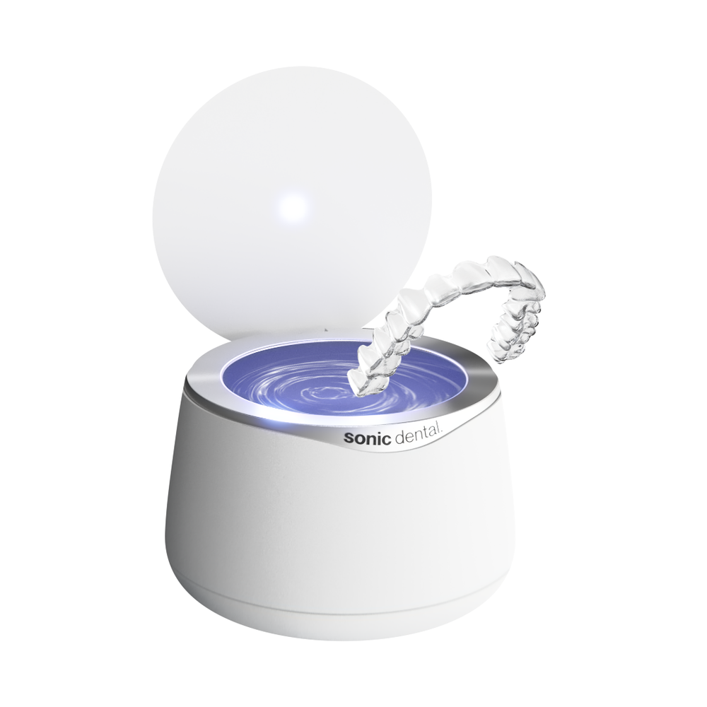 Nettoyeur Sonic Pro blanc avec son couvercle ouvert et un appareil dentaire transparent au-dessus du réservoir — Gearfinch